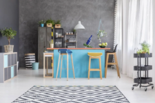 15 a small bright kitchen with a blue kitchen island and a set of mismatching colorful stools