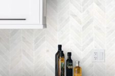 15 a white kitchen with grey stone countertops and a white marble tile herringbone backsplash for a pattern