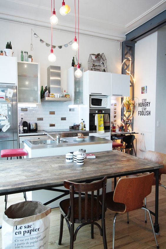 a quirky kitchen with a wooden table and al mismatching chairs and stools at the tables