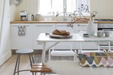 17 a Scandinavian kitchen with a white dining table and mismatching benches, chairs and stools