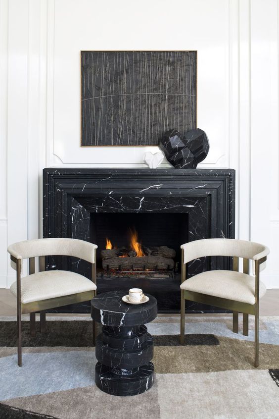 a catchy fireplace nook with a black marble clad fireplace, refined chairs and a black marble side table