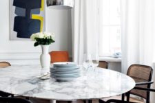 22 a chic white marble round dining table and rattan and cane chairs make up a chic mid-century modern dining zone