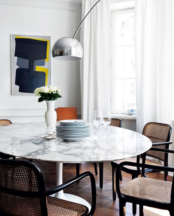 A chic white marble round dining table and rattan and cane chairs make up a chic mid century modern dining zone