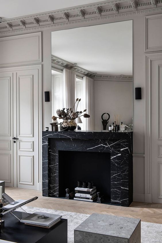A refined living room with a large non working fireplace clad with black marble for a chic touch