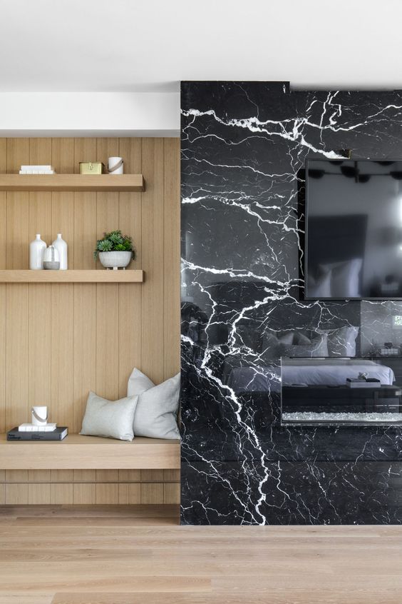 a TV and a built-in fireplace on a black marble panel look super chic and refined