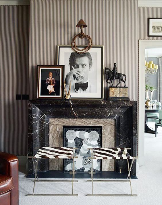 a whimsical fireplace clad with neutral stone and black marble plus artworks and animal print stools