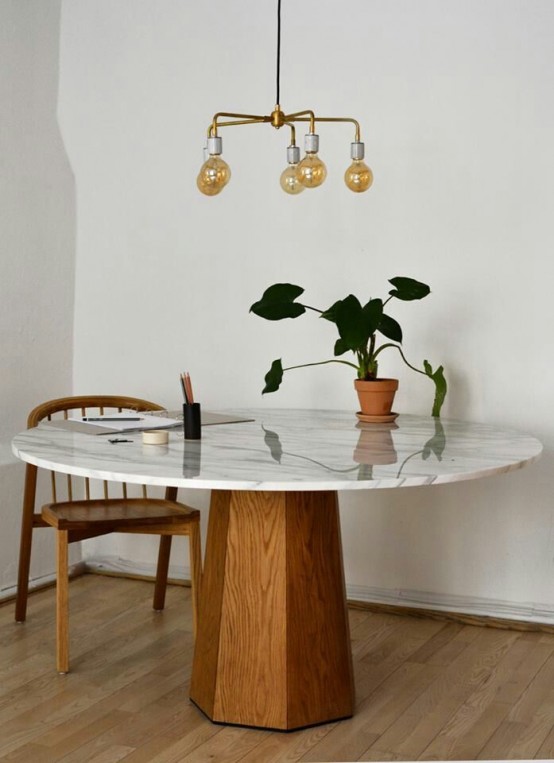 An elegant mid century dining table with a wooden faceted base and a white marble tabletop