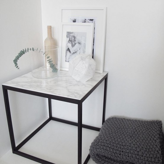 A side table with a black metal base and a white marble countertop   if you can't afford marble, go for contact paper