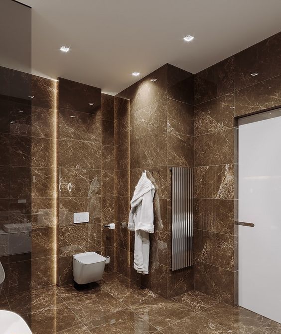 a contemporary brown bathroom clad with brown marble tiles, with white appliances and touches of stainless steel