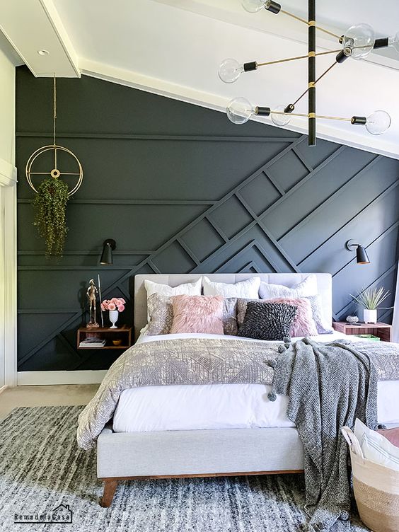 A cozy modern bedroom done in neutrals and with an accent black paneled wall that brings a bit of drama
