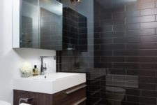 a modern chocolate brown and white bathroom with brown tiles in the shower, a brown vanity and white appliances and walls