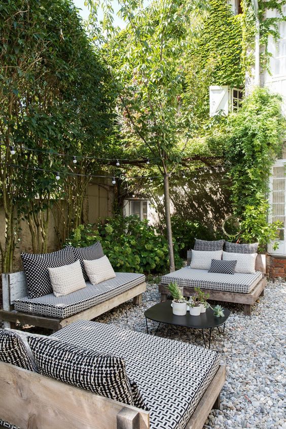 a monochromatic backyard with black and white furniture and lots of greenery around