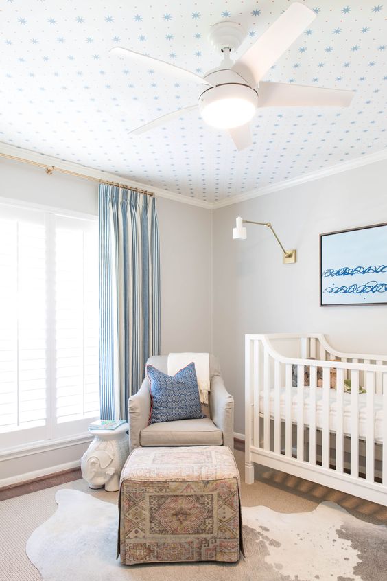 a rather neutral blue and white kid's room made cooler with a printed wallpaper ceiling that adds catchiness to the room