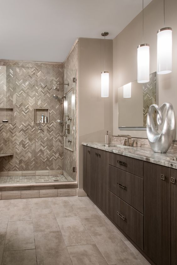 a refined bathroom with tan walls, a dark stained vanity, a tiled shower space and much stone