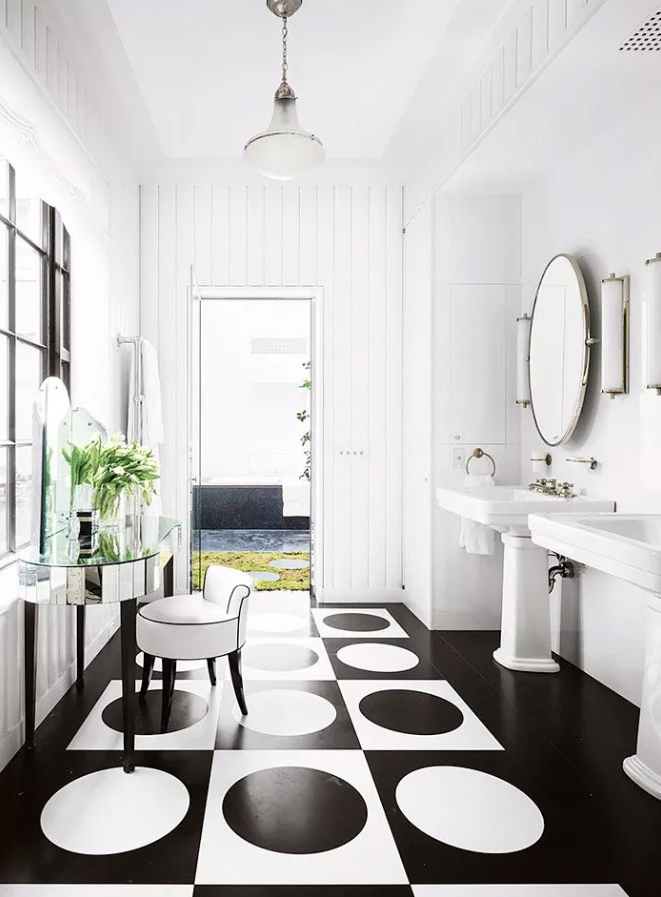 A refined monochromatic bathroom with white beadboard walls, white free standing sinks and an oversized white frame mirror