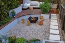 a small and welcoming backyard with a fire pit zone and tree stumps with growing plants and trees, with a raised sitting zone with a sofa