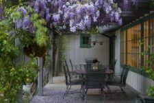 a small backyard covered with wisteria and with an elegant vintage dining set plus greenery around is amazing