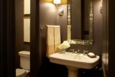 a stylish brown bathroom with a vintage mirror, a free-standing sink and vintage fixtures and lights