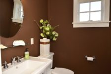 a stylish brown bathroom with white appliances and lamps and a mid-century modern feel