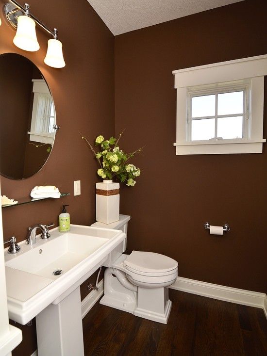 a stylish brown bathroom with white appliances and lamps and a mid-century modern feel