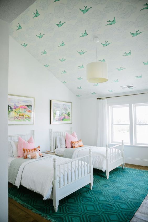 a stylish double guest bedroom with an attic ceiling covered with green bird wallpaper and a matching rug