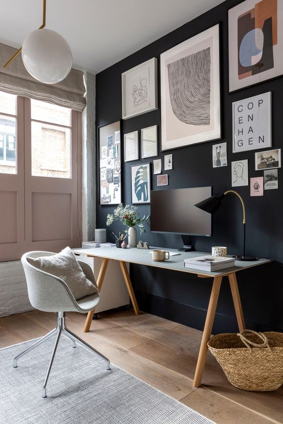 a stylish home office with a black accent wall and a gallery wall, blush doors, neutral walls and upholstery