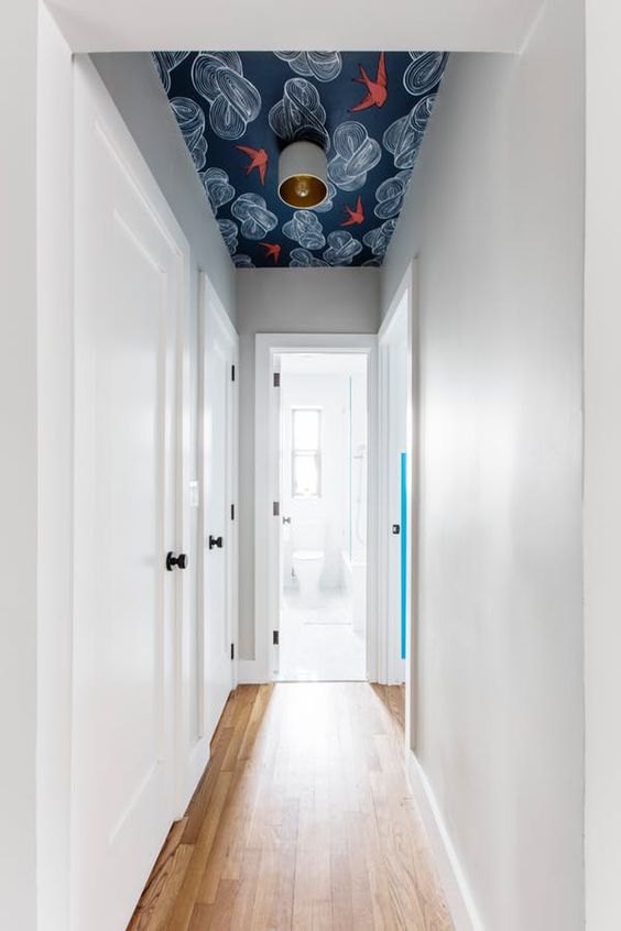 a very narrow and laconic corridor made cool with a bright printed wallpaper ceiling doesn't look small or boring