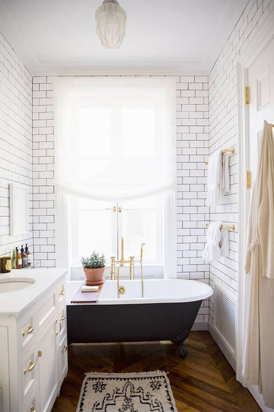 A vintage black clawfoot bathtub and black grout with subway tiles bring more chic to the space