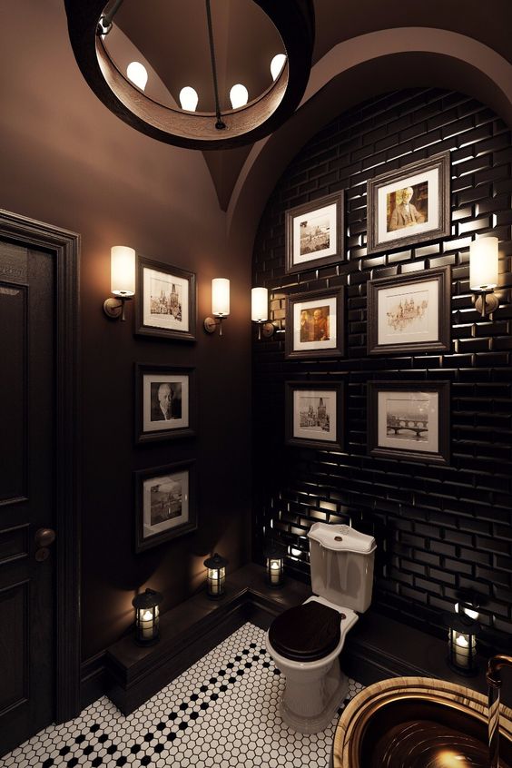an art deco powder room with chocolate brown walls and a tiled wall, a gallery wall and touches of brass