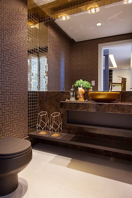 an elegant brown bathroom with printed walls, a brown stone vanity and touches of gold for a glam look