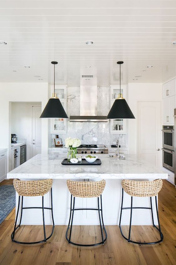 just a couple of black pendant lamps and wicker stools on black legs make the neutral refined kitchen look modern