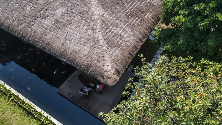 This contemporary Vietnam house features a thatched roof, which is a traditional thing for this part of Vietnam, and a pond to keep the spaces cooler during the day