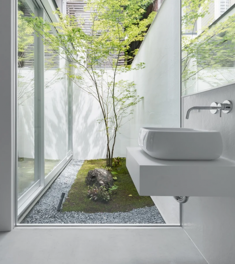 The bathrooms has glazed walls that go to an inner courtyard with rocks and trees - a fusion of nature and modenr design