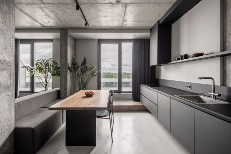 The kitchen is done with sleek grey cabinets, a stylish dining zone with built-in benches and a table and dark linens