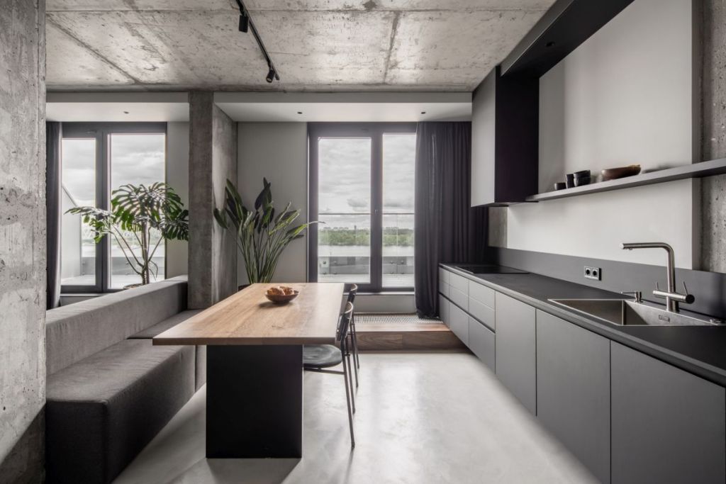 The kitchen is done with sleek grey cabinets, a stylish dining zone with built in benches and a table and dark linens