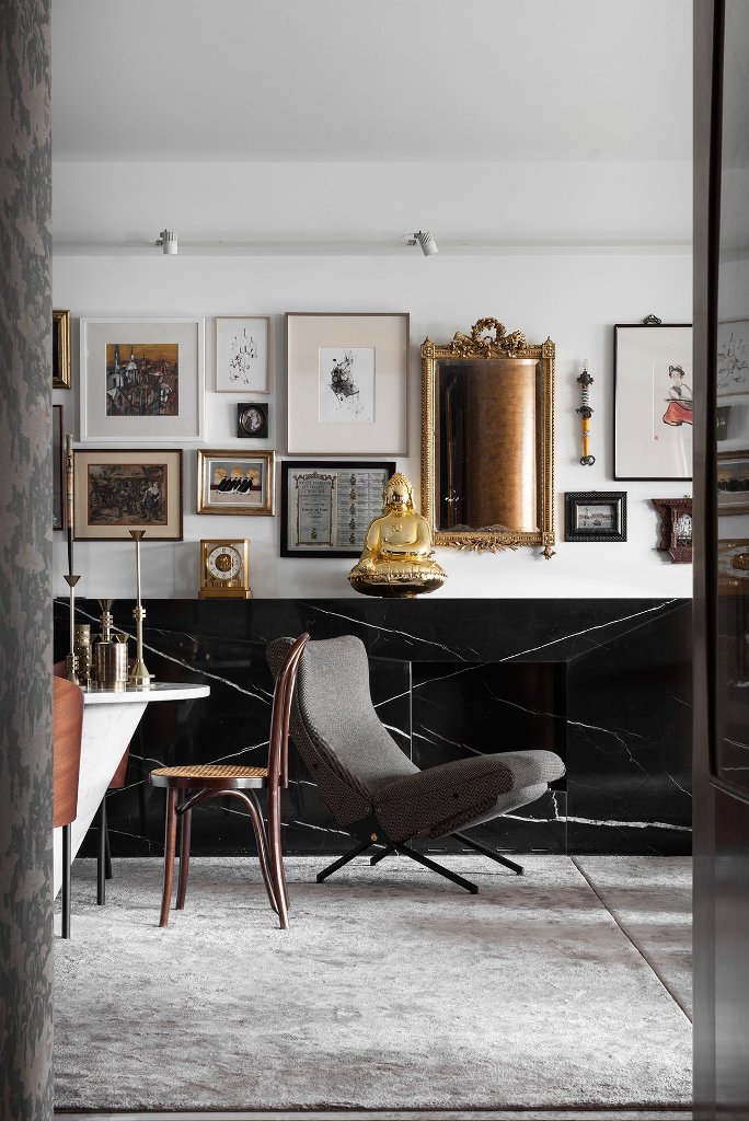 The living room is done in black and white, with a marble fireplace, a gorgeous gallery wall with mirrors and art