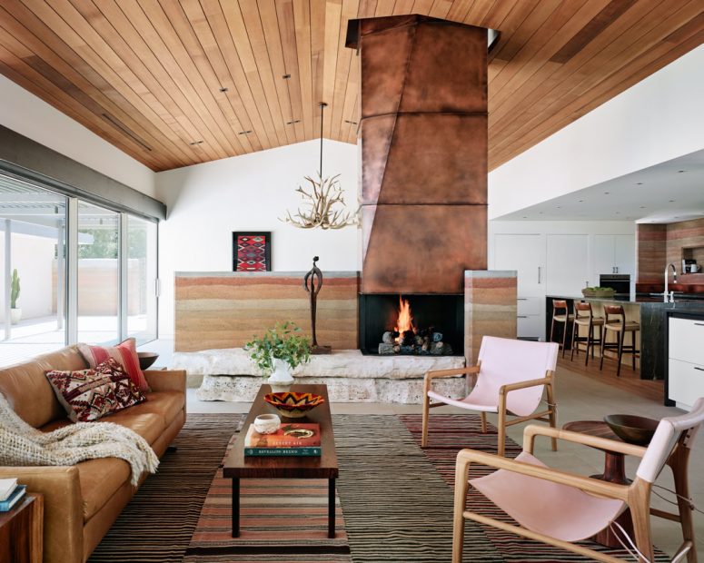 The living room shows off a gorgeous copper clad fireplace on stone, stylish furniture and layered rugs