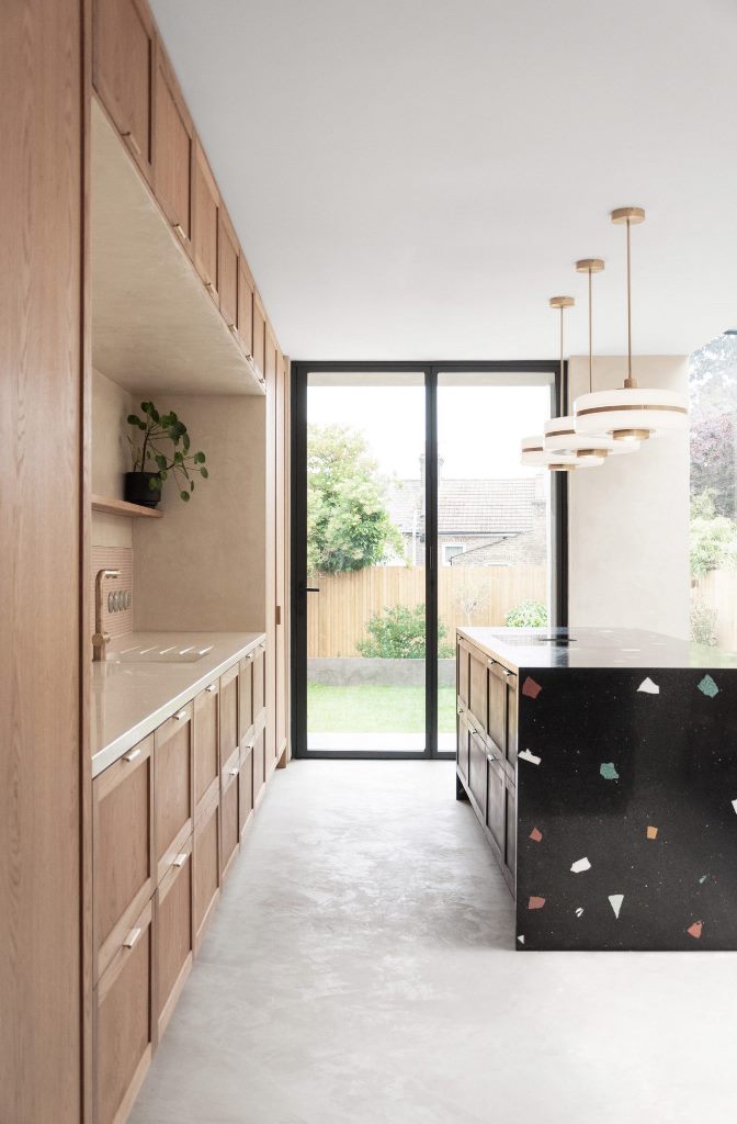 There's a large black terrazzo kitchen island highlighted with pendant lamps