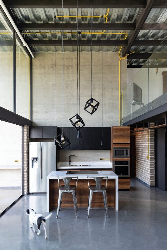 The kitchen is minimalist, it features black upper cabinets, a stained wood kitchen island and gorgeous pendant lamps
