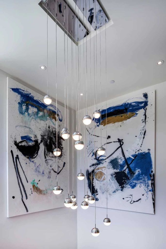 The staircase space is accented with bright artworks and pendant bubble lamps
