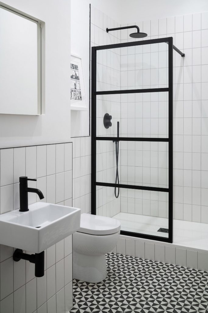 This bathroom is graphic and monochromatic, with matte black fixtures and cool mosaic tiles on the floor