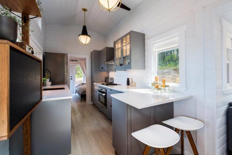 The kitchen is done with grey cabinets, white countertops and there's a small breakfast bar