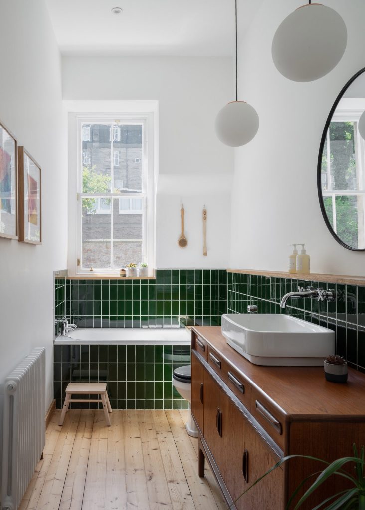 This bathroom shows off grass green tiles, light and rich stained wooden items