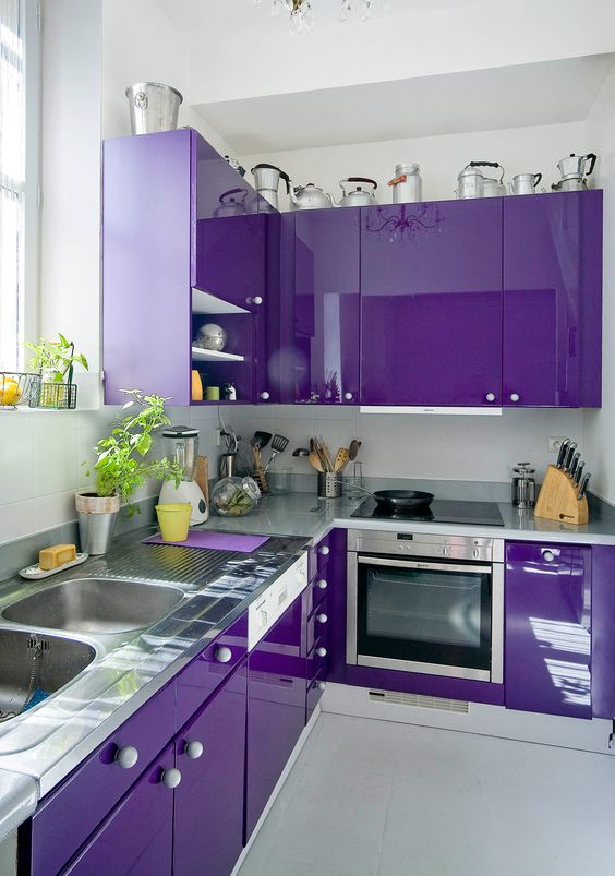 a bold violet kitchen with metal countertops and white knobs is a stylish and super catchy idea