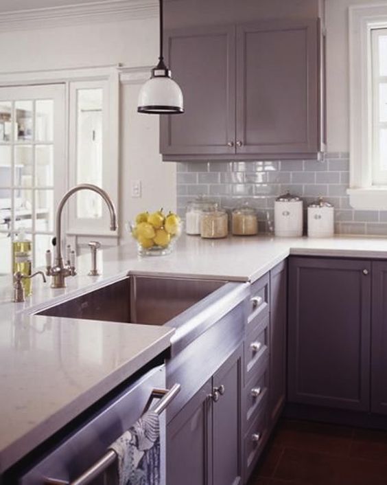 a contemporary lilac kitchen with a white countertop and a backsplash plus white pendant lamps