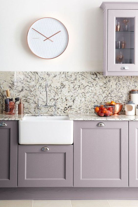 a modern grey lilac kitchen with stone countertops and a backsplash, with a white clock and sink looks very chic