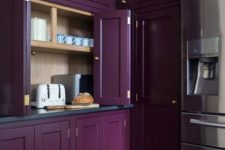a moody vintage purple kitchen all clad with doors and panels and with gold knobs for an accent