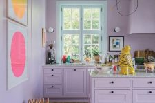 a quirky lilac kitchen with grey stone countertops and bright artworks on the wall is a very catchy space to be