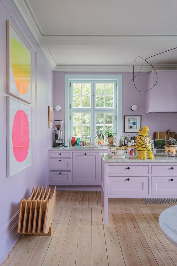 a quirky lilac kitchen with grey stone countertops and bright artworks on the wall is a very catchy space to be