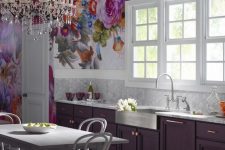 a refined purple kitchen with marble hex tiles, an oversized bright floral artwork and a crystal chandelier